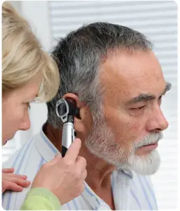 Professional audiologist examining a patient’s ear for blockages.